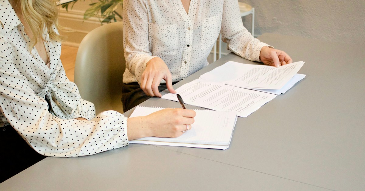 Hands reviewing and signing mortgage paperwork at a table